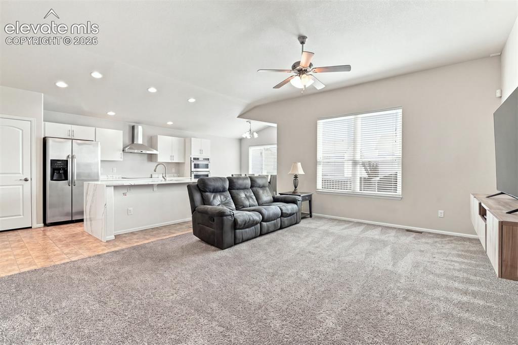 Image 6 of 32: Open-concept living space featuring a kitchen with stainless steel applianc