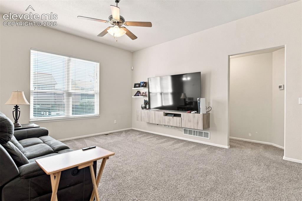 Image 7 of 32: Recessed ceiling with ceiling fan, large window with blinds, light gray wal
