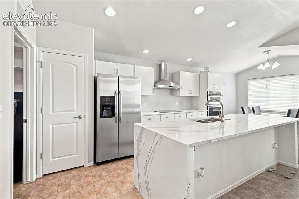 Image 9 of 32: Kitchen featuring white cabinetry, stainless steel appliances, a large isla