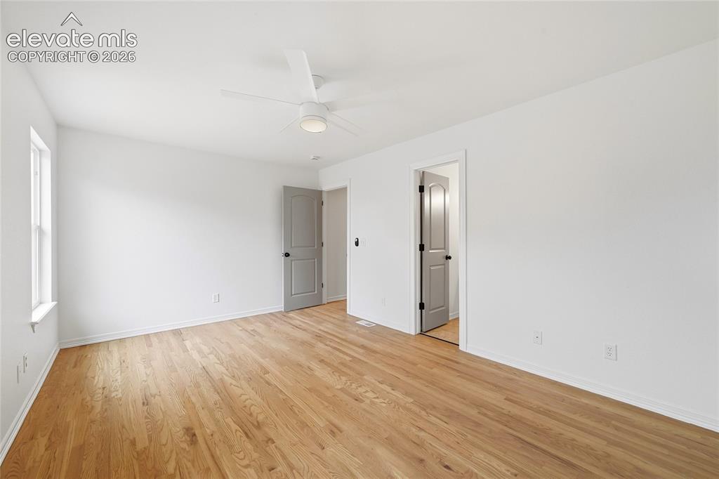 Image 12 of 30: Spacious room featuring wood-finish flooring and a contemporary ceiling fan