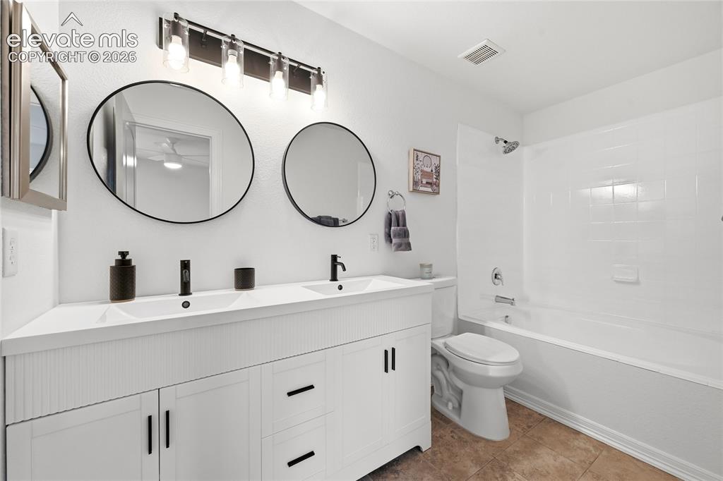 Image 13 of 30: Dual vanity with integrated sinks, black hardware, and two circular mirrors