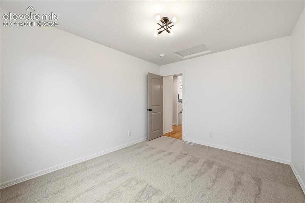 Image 16 of 30: Room featuring light gray carpeting, crisp white walls, and a contemporary