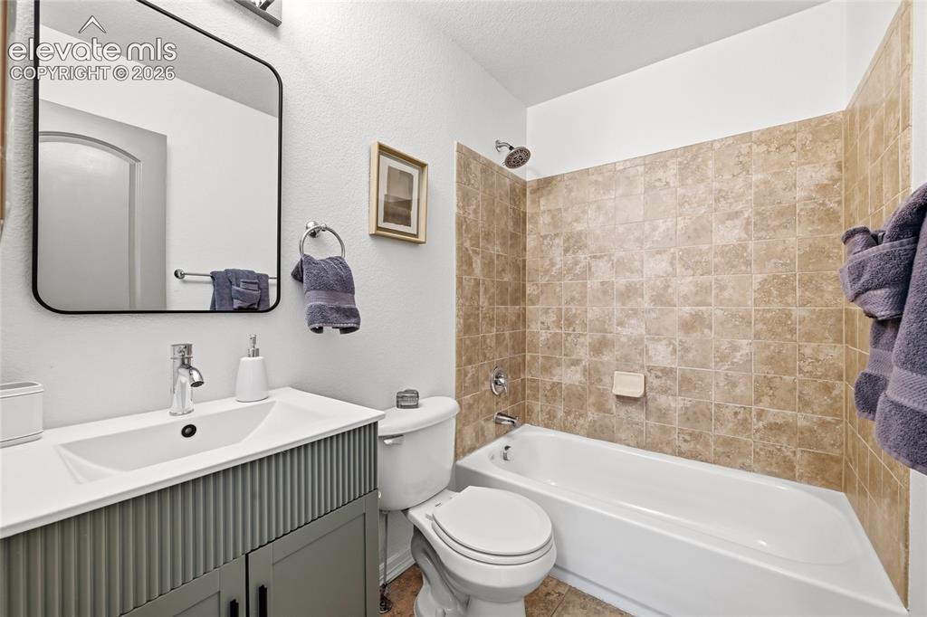 Image 18 of 30: Bathroom featuring a white bathtub with a tiled surround, a contemporary va