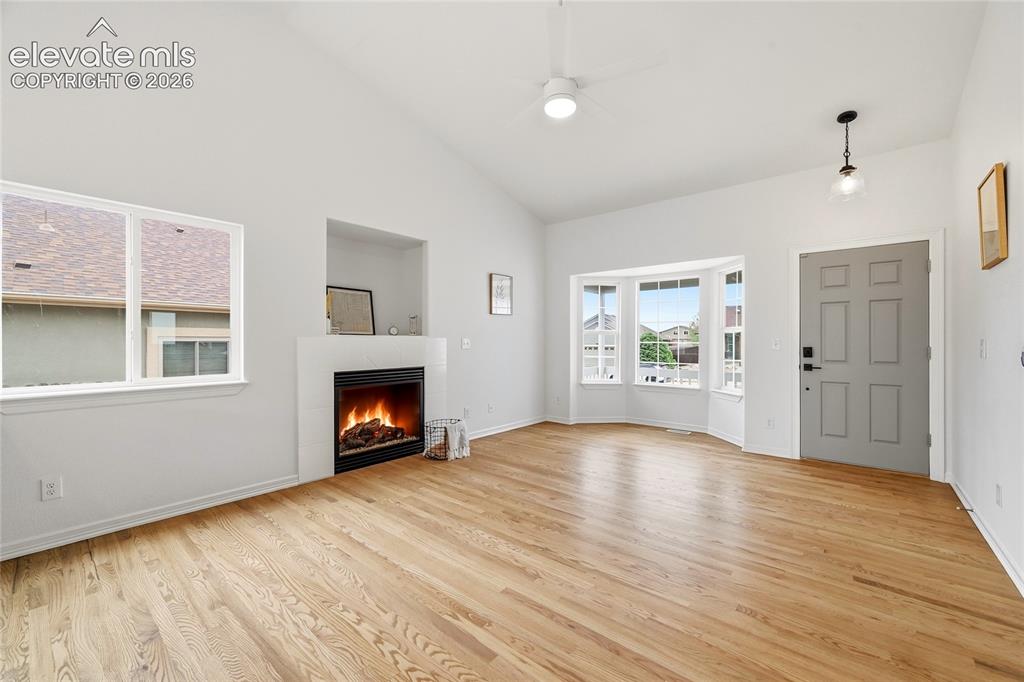 Image 2 of 30: Spacious living area featuring wood-finish flooring, a modern fireplace wit