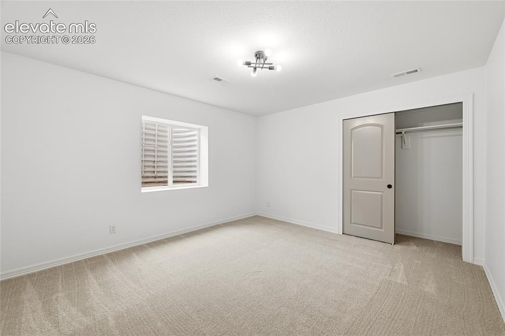Image 23 of 30: Carpeted room with white walls, a single window with horizontal blinds, and