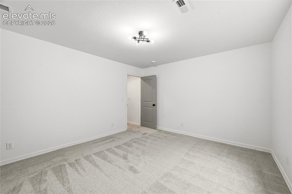 Image 24 of 30: Spacious room featuring neutral carpeting, white painted walls, a gray inte