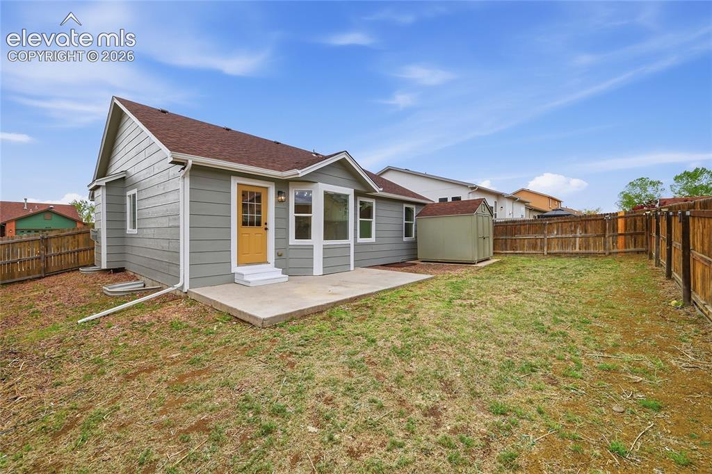 Image 25 of 30: Rear exterior featuring a concrete patio, gabled roofline, and bay window