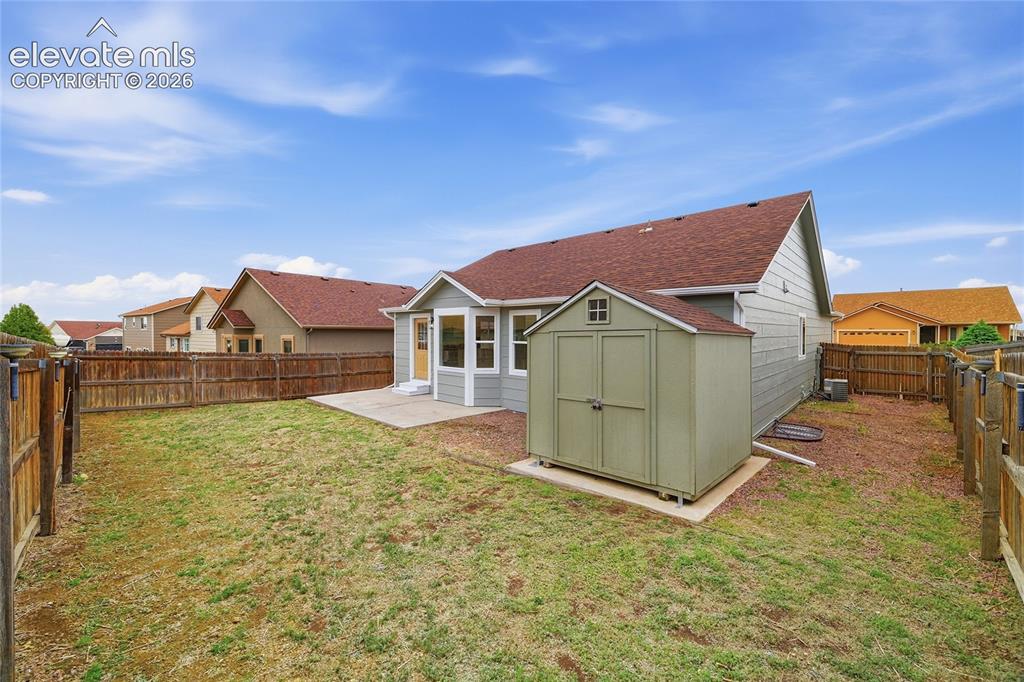 Image 26 of 30: Expansive backyard featuring a privacy fence, concrete patio, and a utility