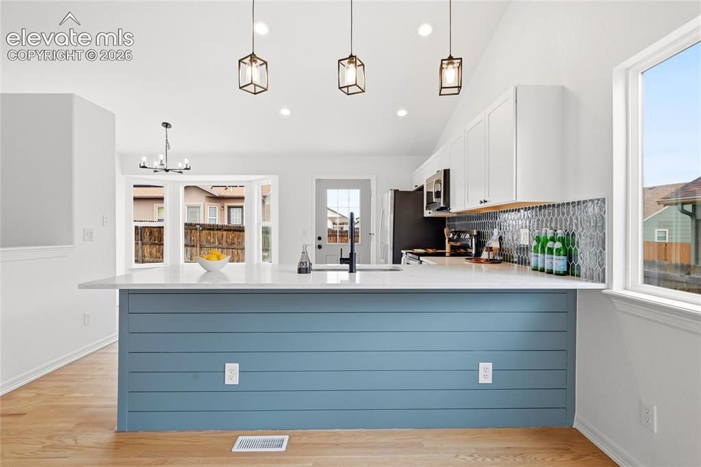 Image 3 of 30: Modern kitchen island featuring a white countertop and blue shiplap-style p