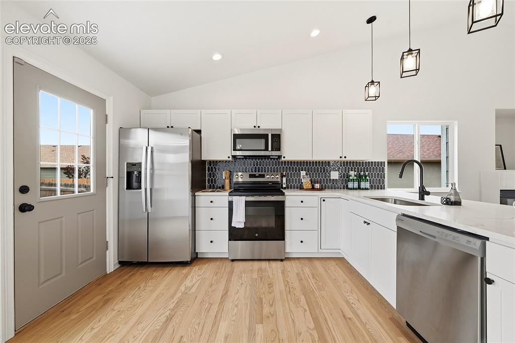 Image 7 of 30: Modern kitchen featuring stainless steel appliances, white cabinetry, wood-