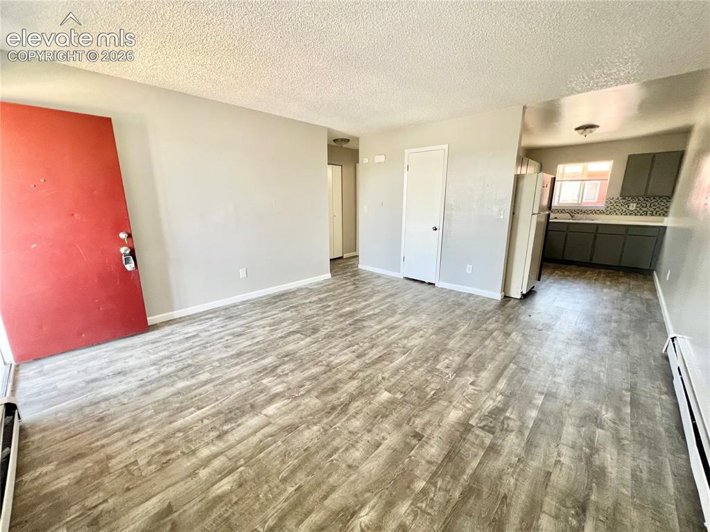 Image 14 of 23: Spacious living area featuring wood-finish flooring, light-toned walls, and