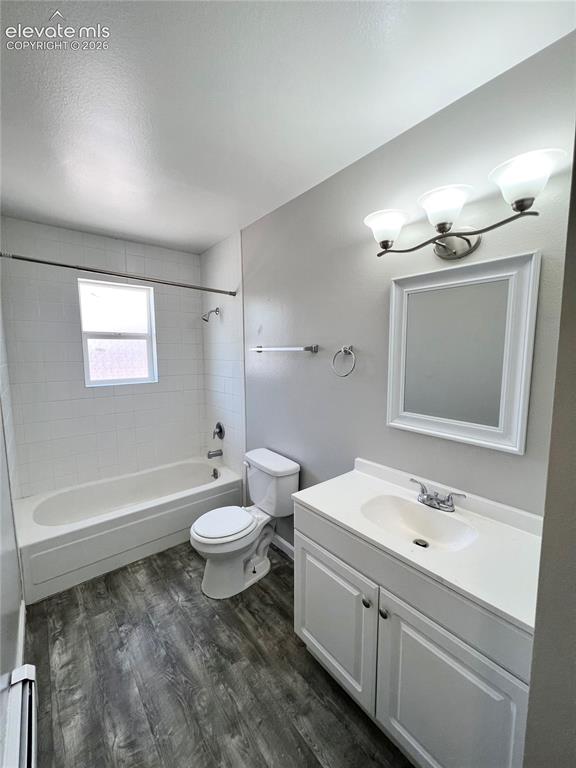 Image 16 of 23: Bathroom featuring a white bathtub with subway tile surround, wood-finish f