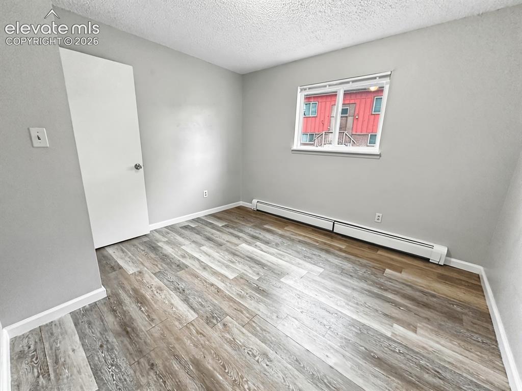 Image 20 of 23: Room featuring wood-finish flooring, a white window frame, and a white door