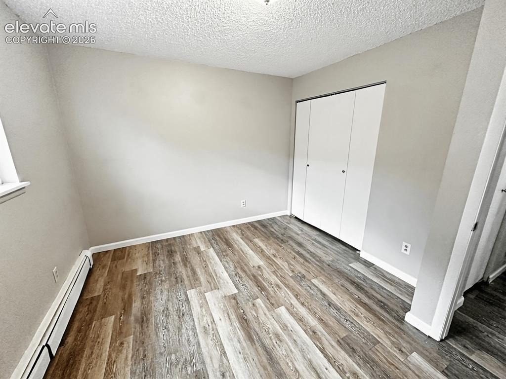 Image 7 of 23: Room featuring wood-finish flooring, a double-door closet, baseboard heatin