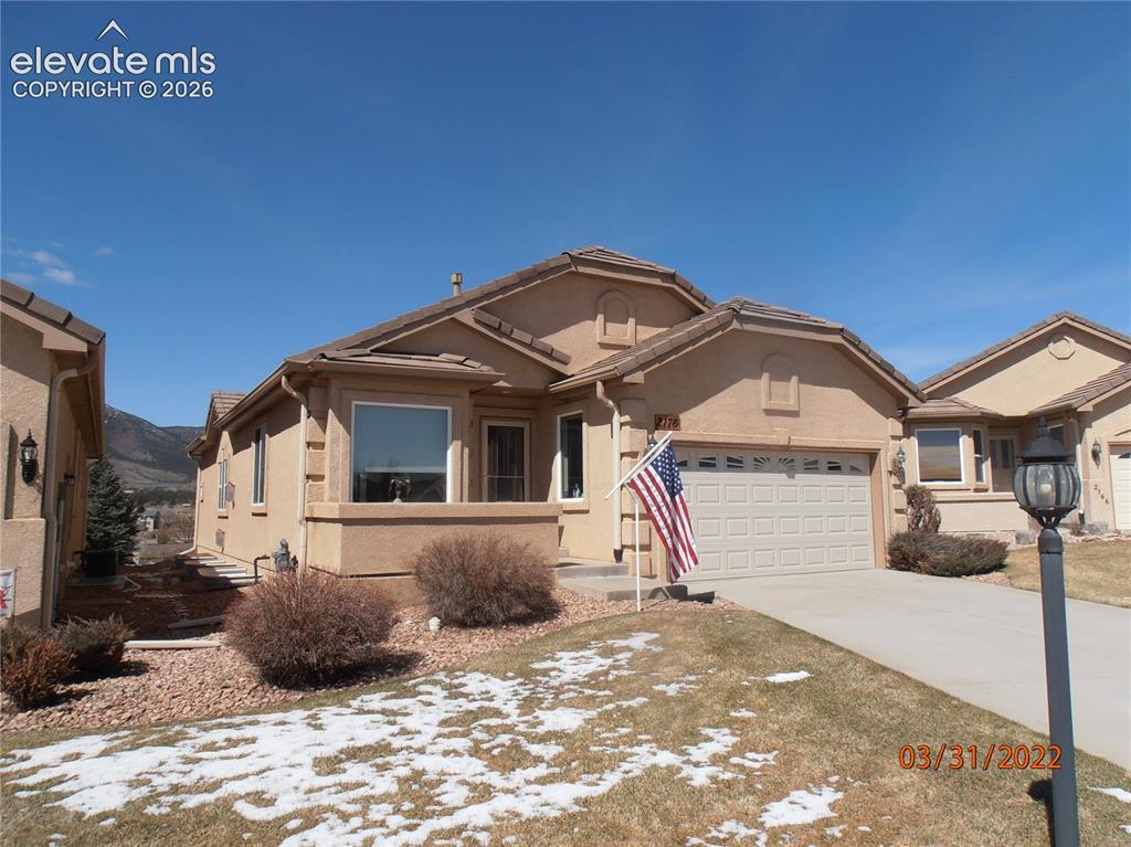 Caption: Stucco exterior featuring a two-car garage, concrete driveway, and front landscaping with rock and s