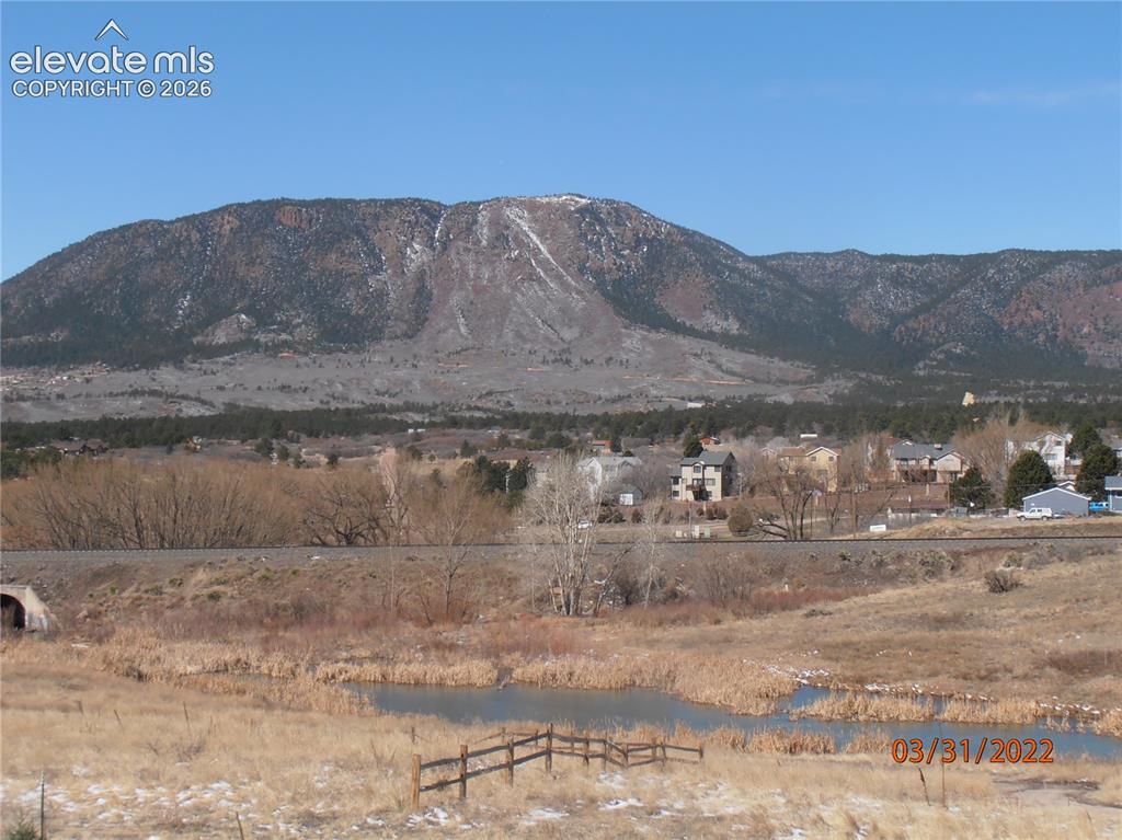 Image 2 of 11: Mountainous backdrop featuring scattered trees and visible snowcaps