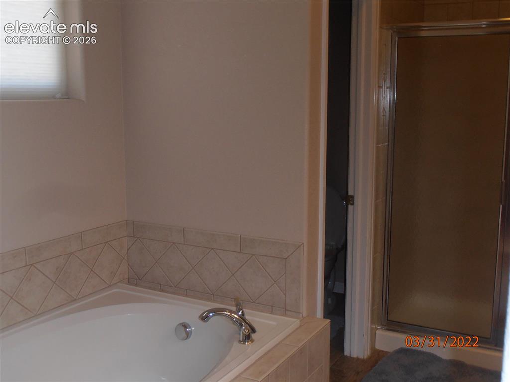 Image 4 of 11: Bathroom featuring a built-in soaking tub with a tiled surround, a chrome f