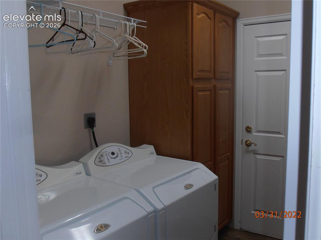 Image 5 of 11: Laundry area featuring a built-in wood-finish storage cabinet, white panel 