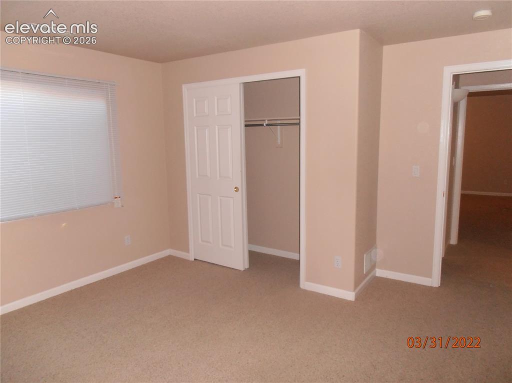 Image 7 of 11: Carpeted interior room with neutral-toned walls, white trim, and a window w