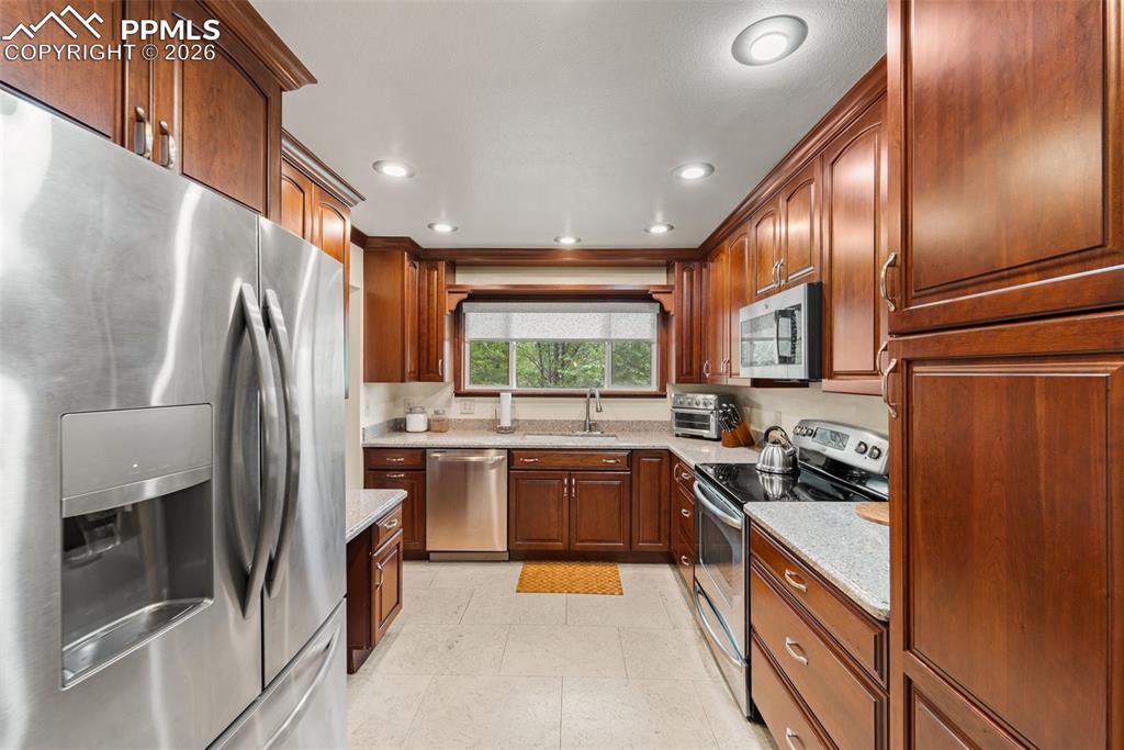 Image 11 of 41: Kitchen featuring stainless steel appliances, light stone countertops, rece