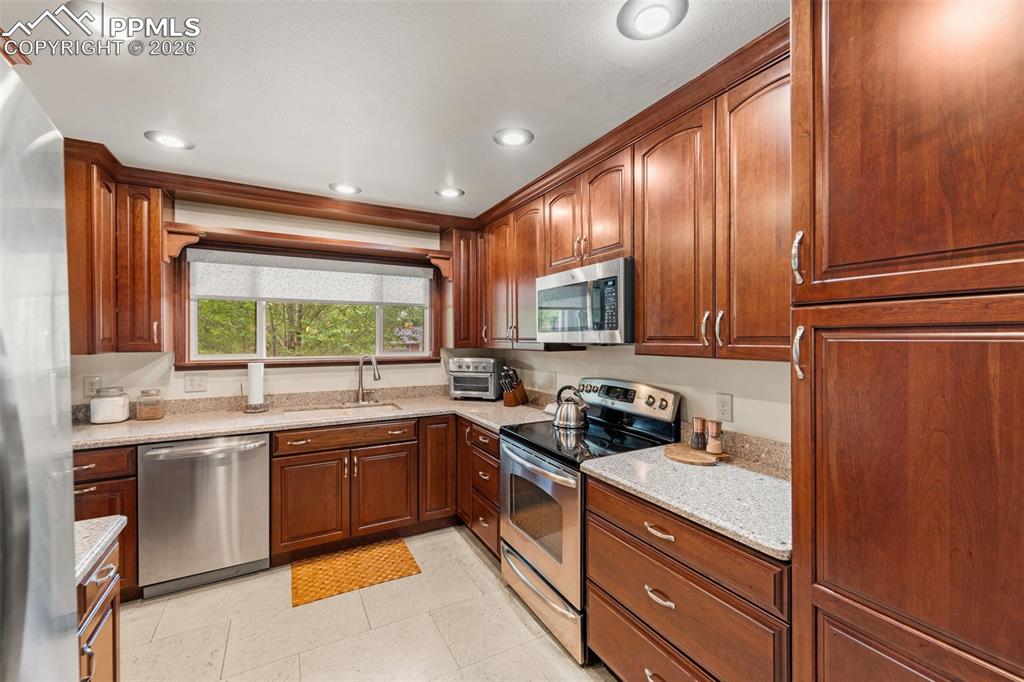 Image 12 of 41: Kitchen featuring stainless steel appliances, light stone counters, recesse