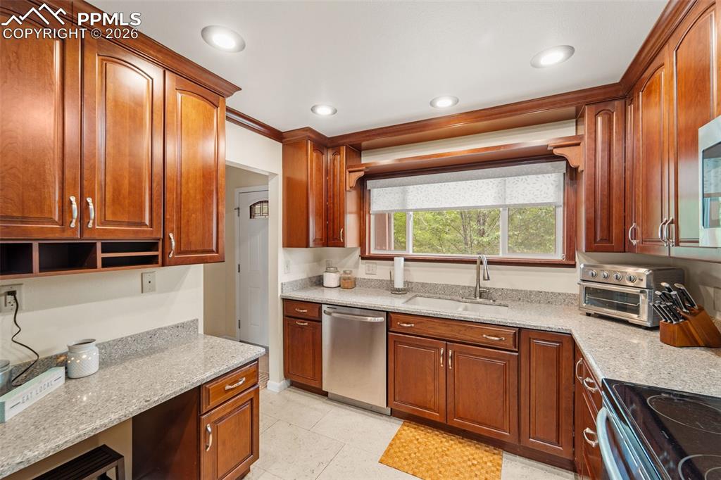 Image 13 of 41: Kitchen featuring light stone counters, crown molding, dishwasher, black ra