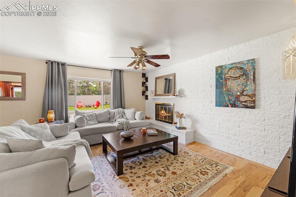 Image 14 of 41: Living area featuring wood finished floors, a ceiling fan, and a fireplace
