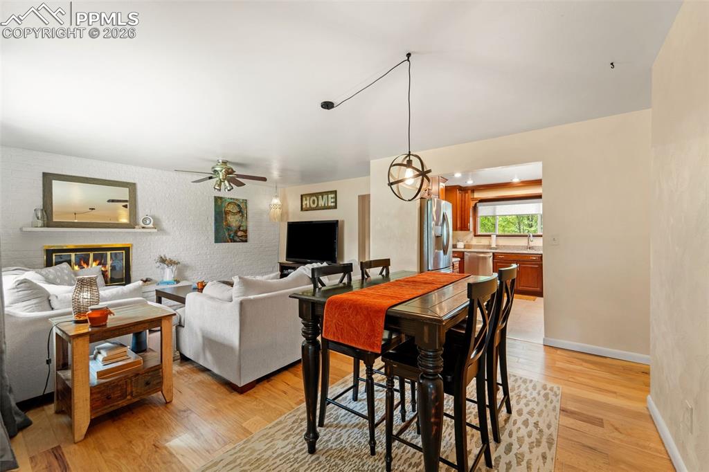 Image 17 of 41: Dining area featuring light wood-style flooring, a glass covered fireplace,