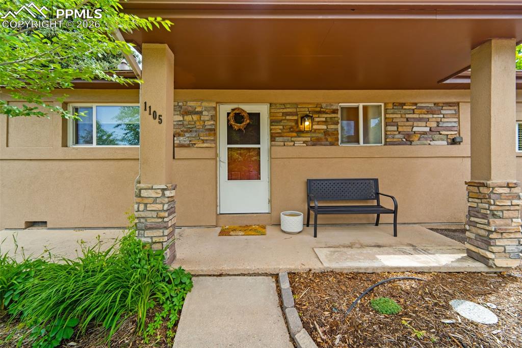 Image 2 of 41: Doorway to property with stone siding, stucco siding, and a porch