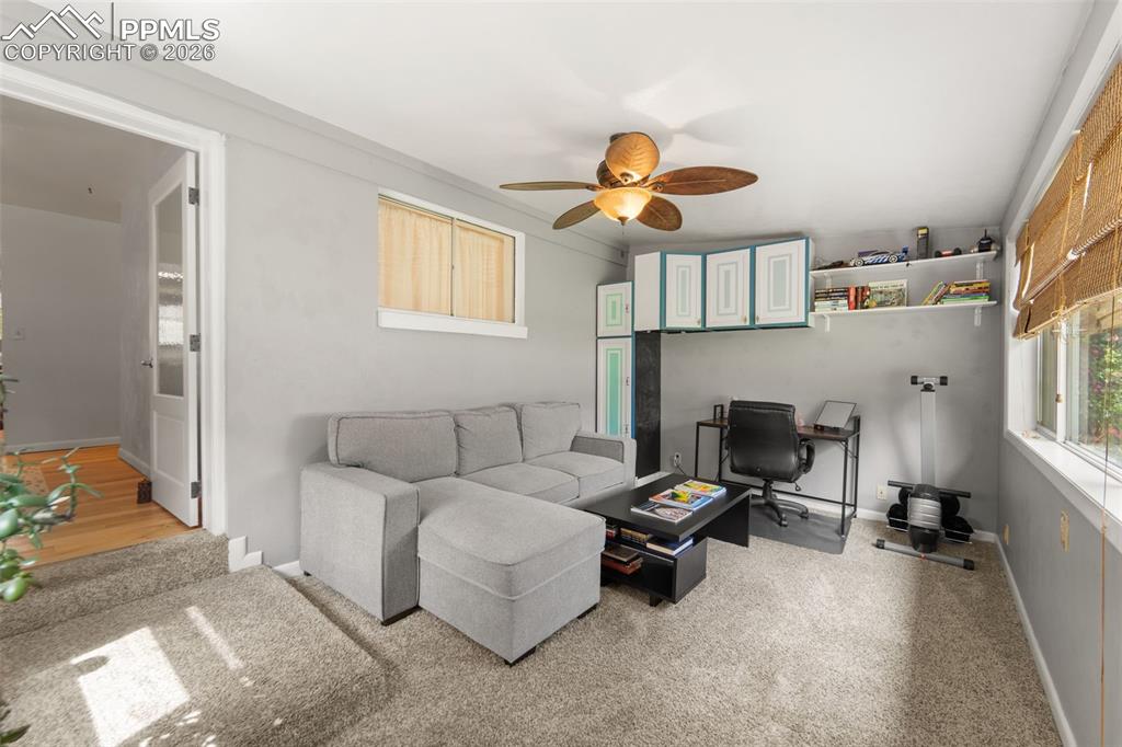 Image 21 of 41: Living room featuring a ceiling fan, light colored carpet, and an office ar