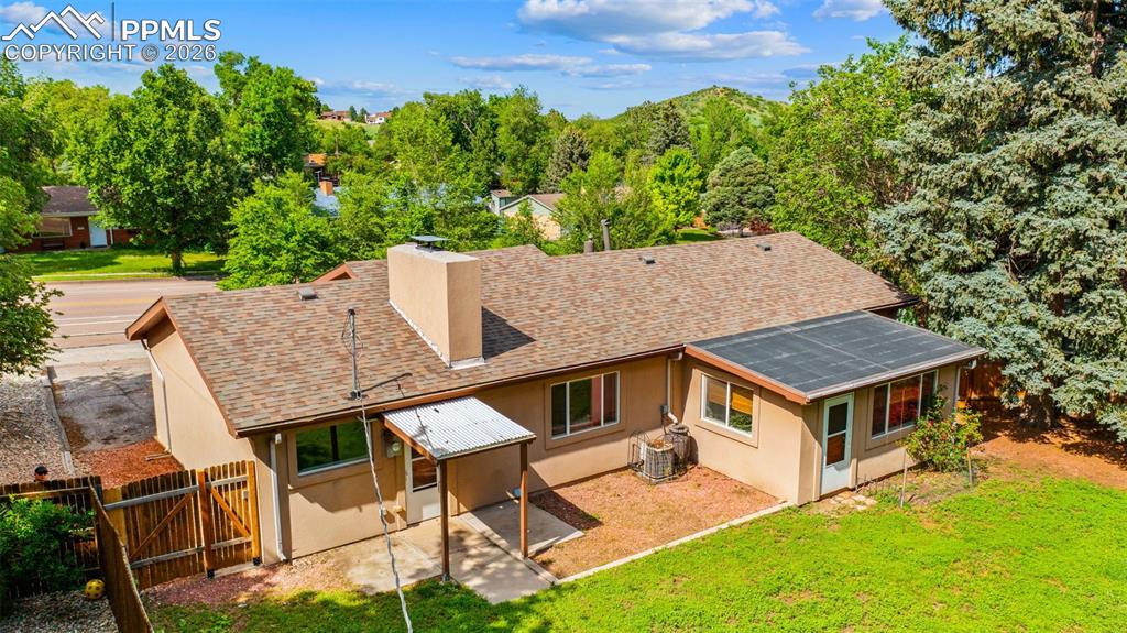 Image 38 of 41: Back of property featuring stucco siding, a chimney, a shingled roof, solar