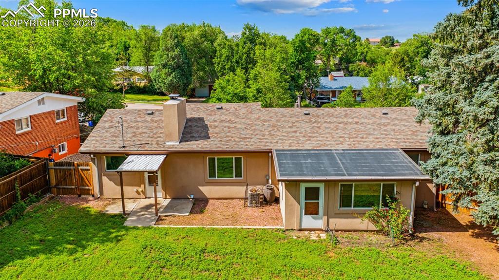 Image 7 of 41: Rear view of house with stucco siding, a fenced backyard, a chimney, and ro