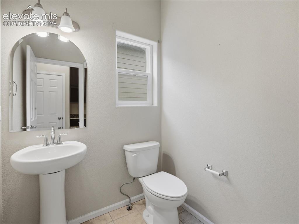 Image 14 of 45: Bathroom featuring a pedestal sink with chrome fixtures, an arched mirror,