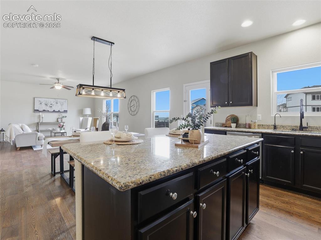 Image 16 of 45: Central kitchen island featuring a light-toned granite countertop and dark