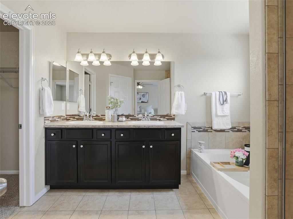 Image 24 of 45: Dual vanity with dark wood cabinetry, light-toned countertop, and tile floo