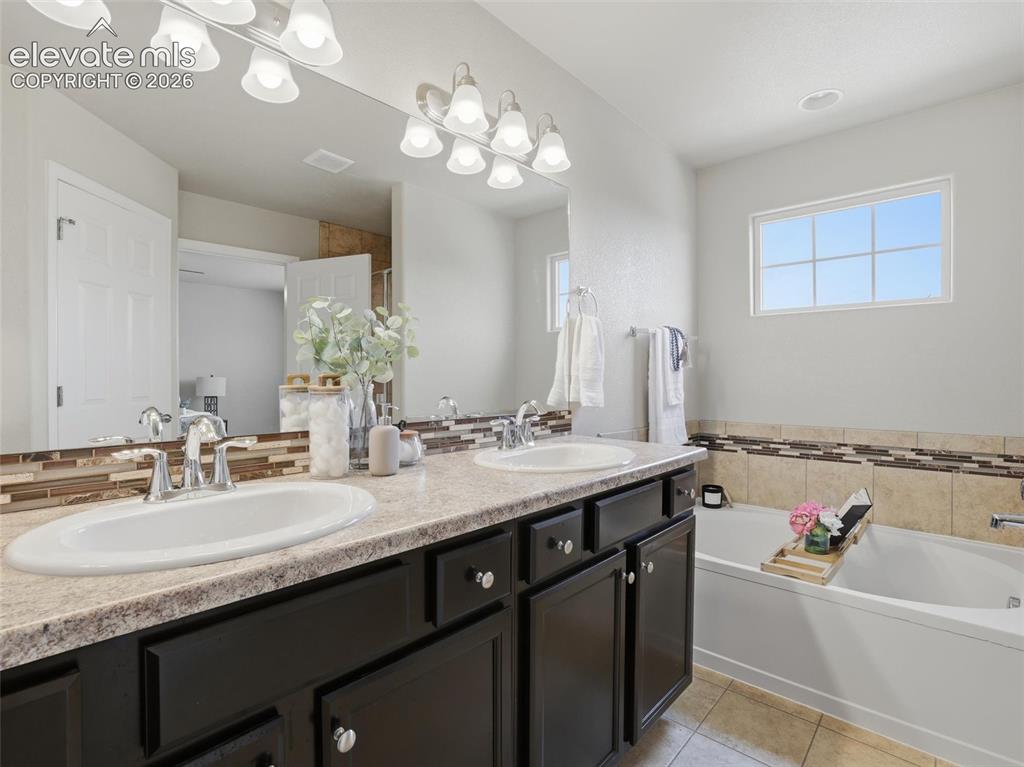 Image 25 of 45: Bathroom vanity featuring dual sinks with chrome fixtures, a large mirror,