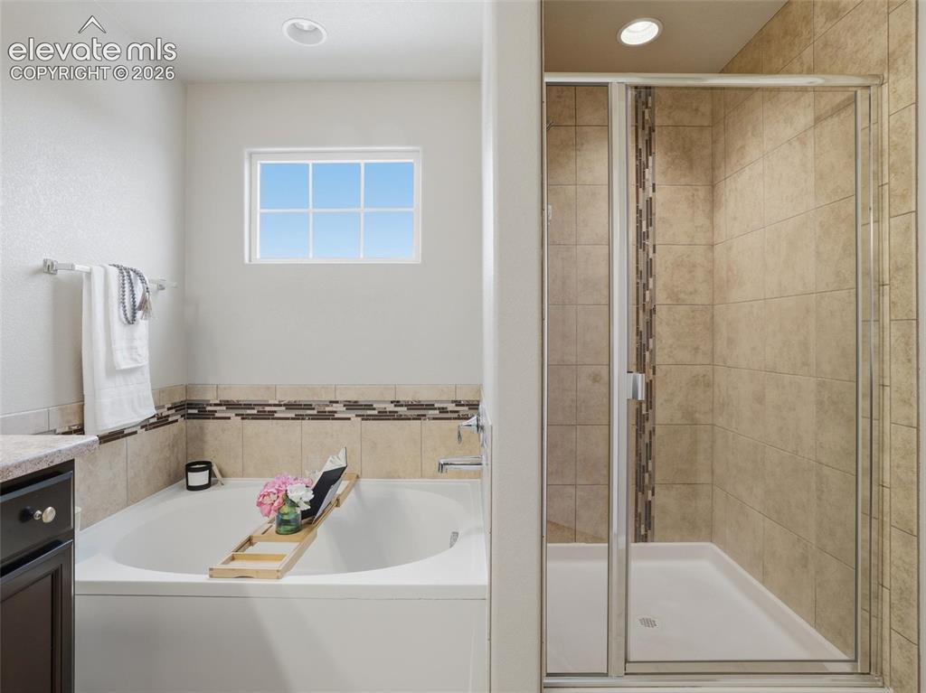 Image 26 of 45: Bathroom featuring a built-in soaking tub, a separate glass-enclosed shower