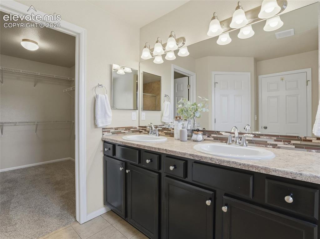 Image 27 of 45: Double vanity with integral sinks, dark cabinetry, and a light-toned counte