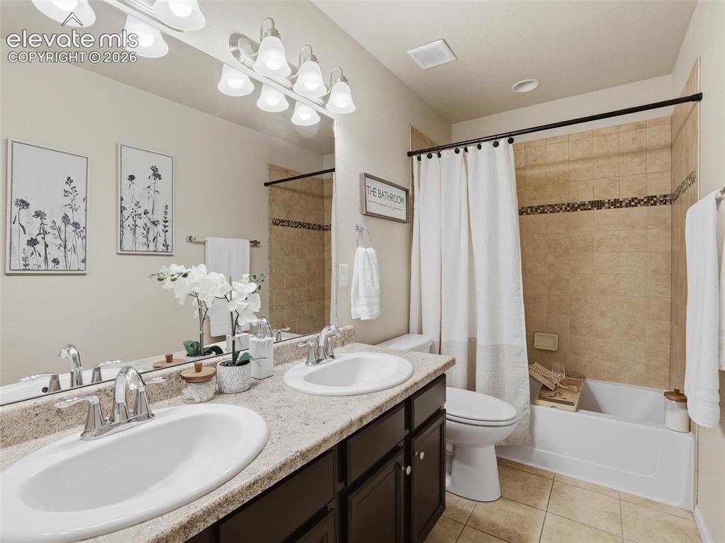 Image 34 of 45: Bathroom featuring a dual-sink vanity with a speckled countertop, dark wood
