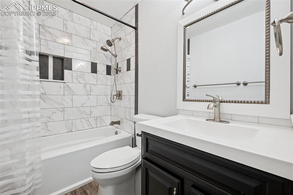 Image 16 of 31: Full bath with washtub / shower combination, vanity, and wood laminate floo