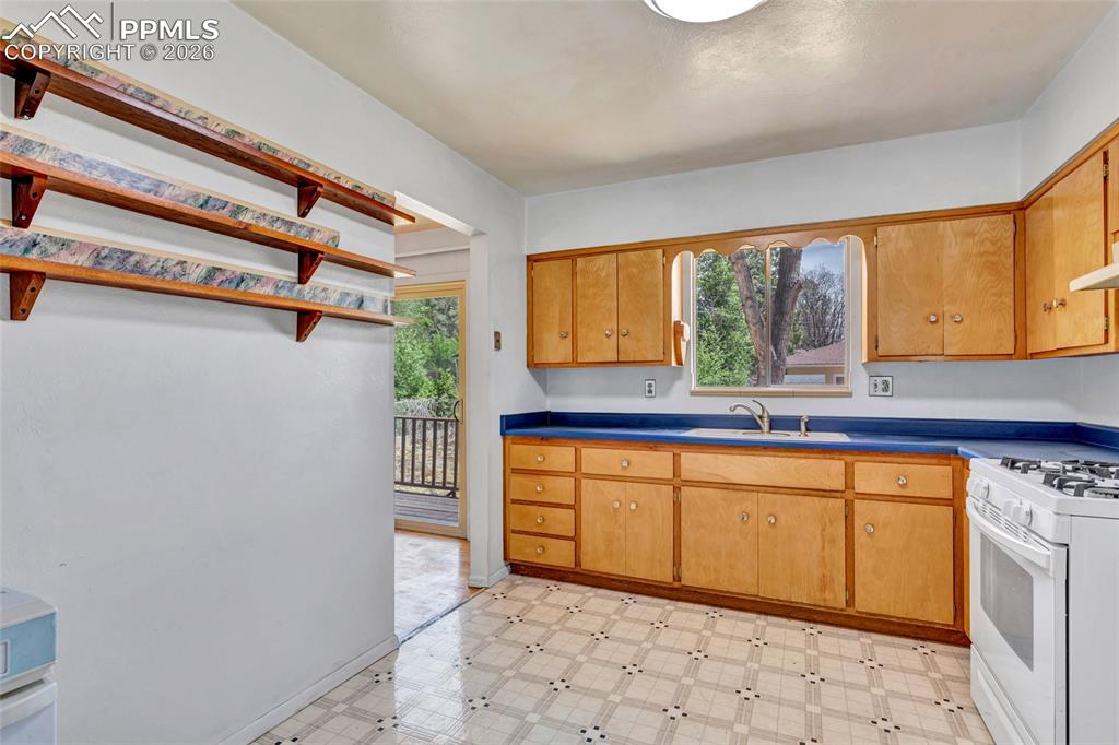 Image 13 of 36: Kitchen featuring wood-finish cabinetry, blue countertops, and white applia
