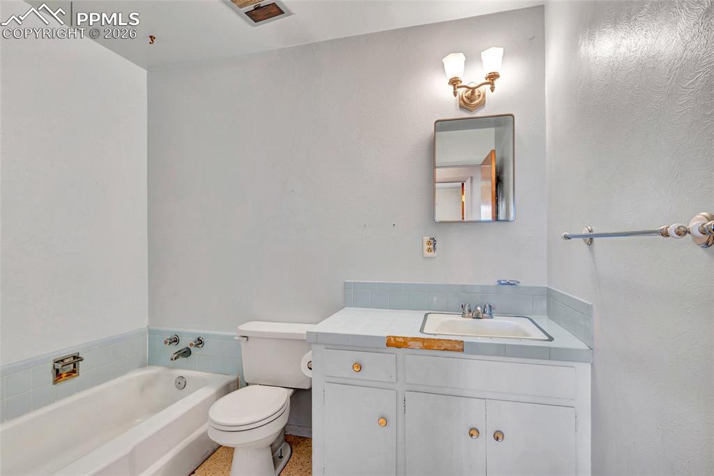 Image 14 of 36: Bathroom featuring a built-in tub with light blue tile surround, a white to