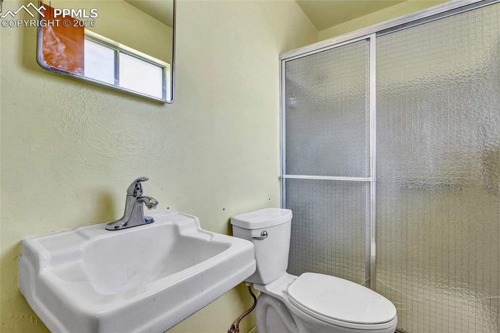 Image 17 of 36: Compact bathroom featuring a wall-mounted sink with chrome faucet, toilet, 