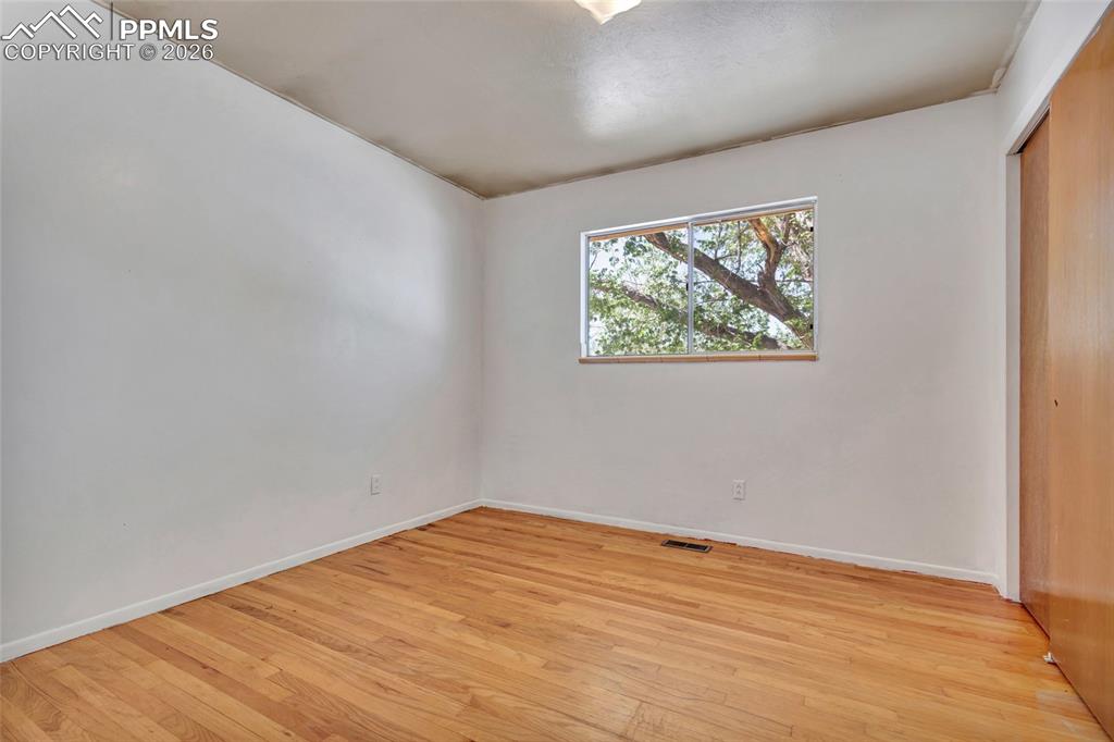 Image 18 of 36: Room featuring wood-finish flooring, a rectangular window with tree foliage