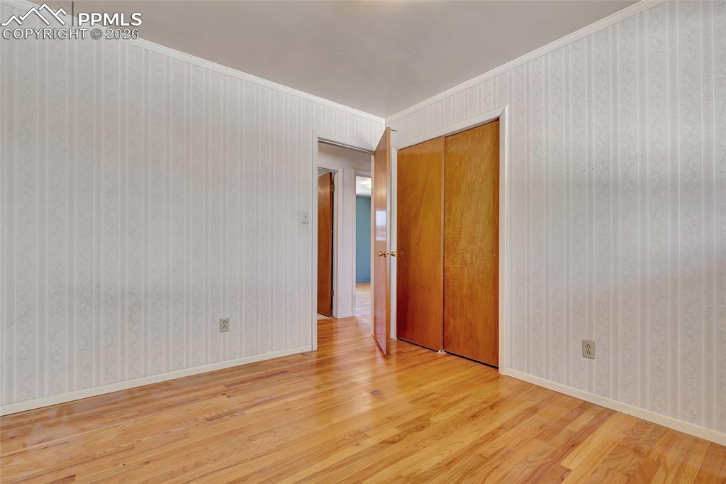 Image 21 of 36: Room featuring wood-finish flooring, patterned wallpaper, a closet with bi-