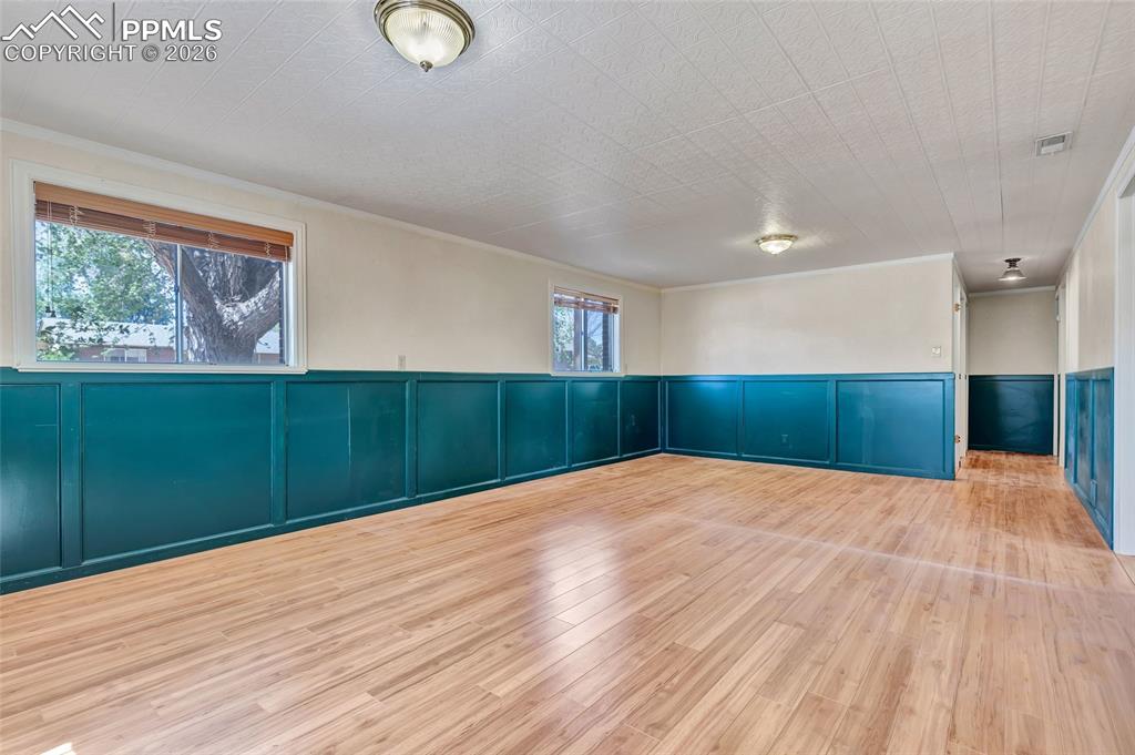 Image 23 of 36: Spacious room featuring wood-finish flooring, wainscoting with a teal finis