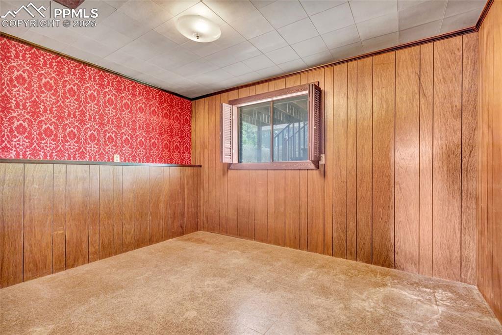Image 26 of 36: Room featuring wood paneling, red patterned wallpaper, a window with interi