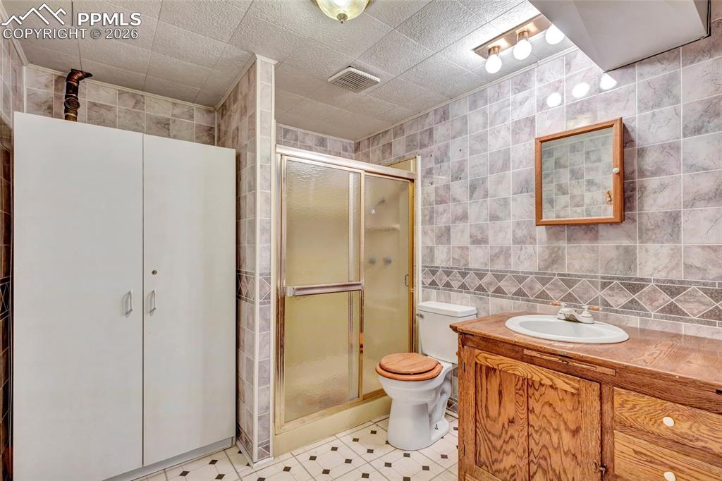 Image 27 of 36: Full bathroom featuring a shower enclosure, a wood-finish vanity with an in