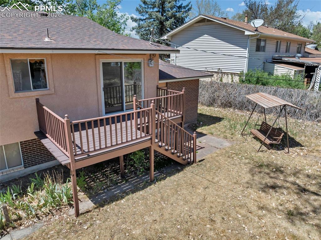 Image 30 of 36: Rear exterior featuring a raised deck with wood-finish railing and stairs