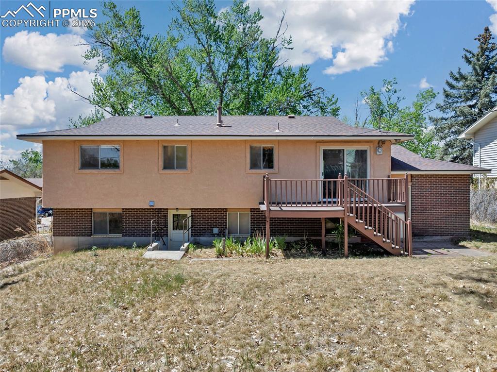 Image 31 of 36: Two-story residence featuring a wood deck with stairs, a sliding glass door